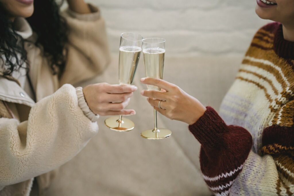 Las mujeres chocan las copas con el champán en la habitación