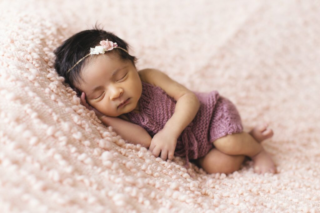 ピンクのフリースパッドの上に横たわる幼児