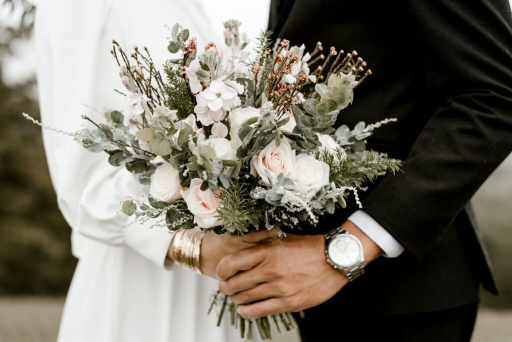 Bridge And Groom Standing While Holding Flower Bouquet