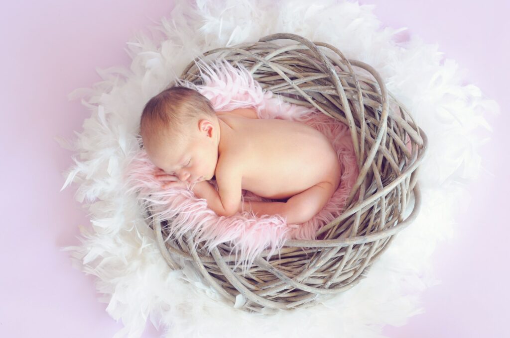 Bebé durmiendo en una cesta y una pluma redonda rodeando la cesta