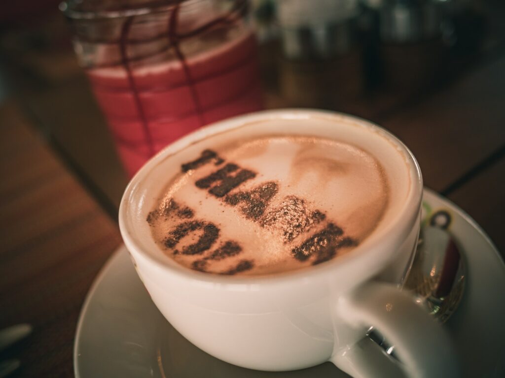 Tasse aromatischer Cappuccino mit Dankesworten auf Schaum