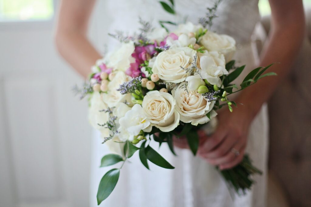 Mariée tenant un bouquet de roses blanches