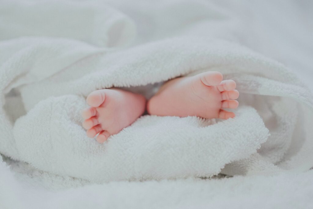 barfüßiges Baby mit weißer Decke