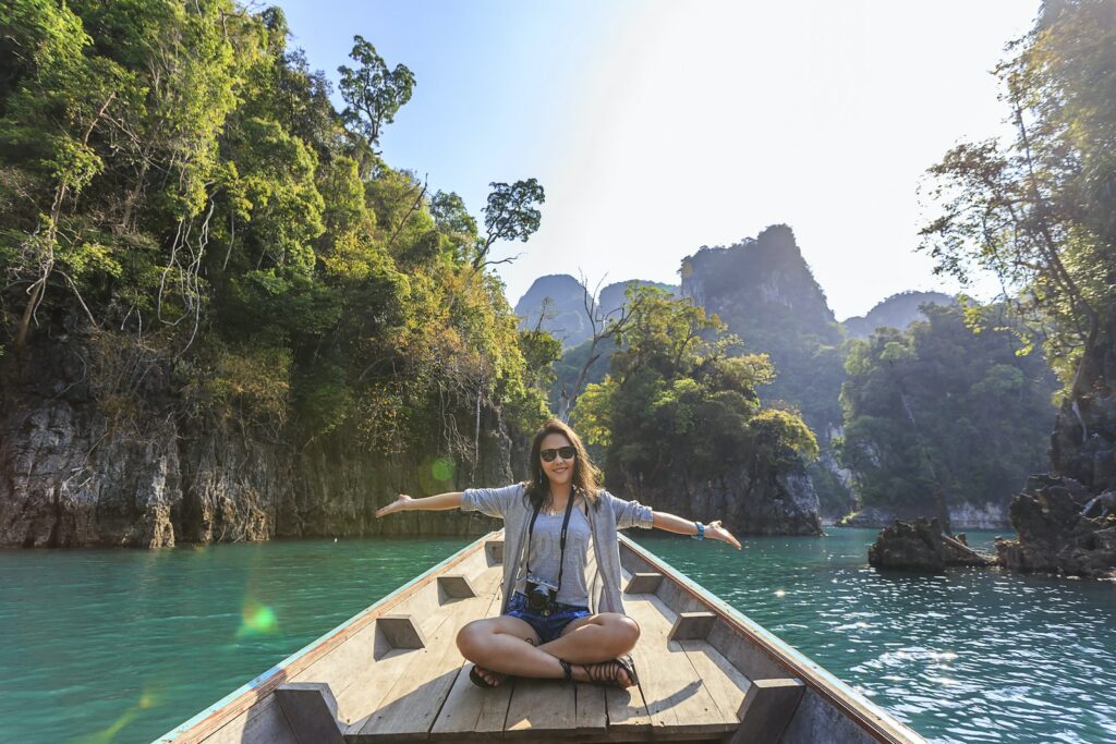 Foto de una mujer sentada en un barco con los brazos abiertos