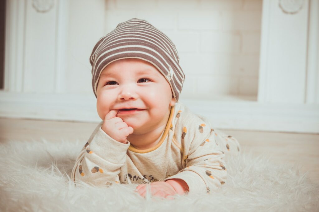 Lächelndes Baby beißt in den rechten Zeigefinger