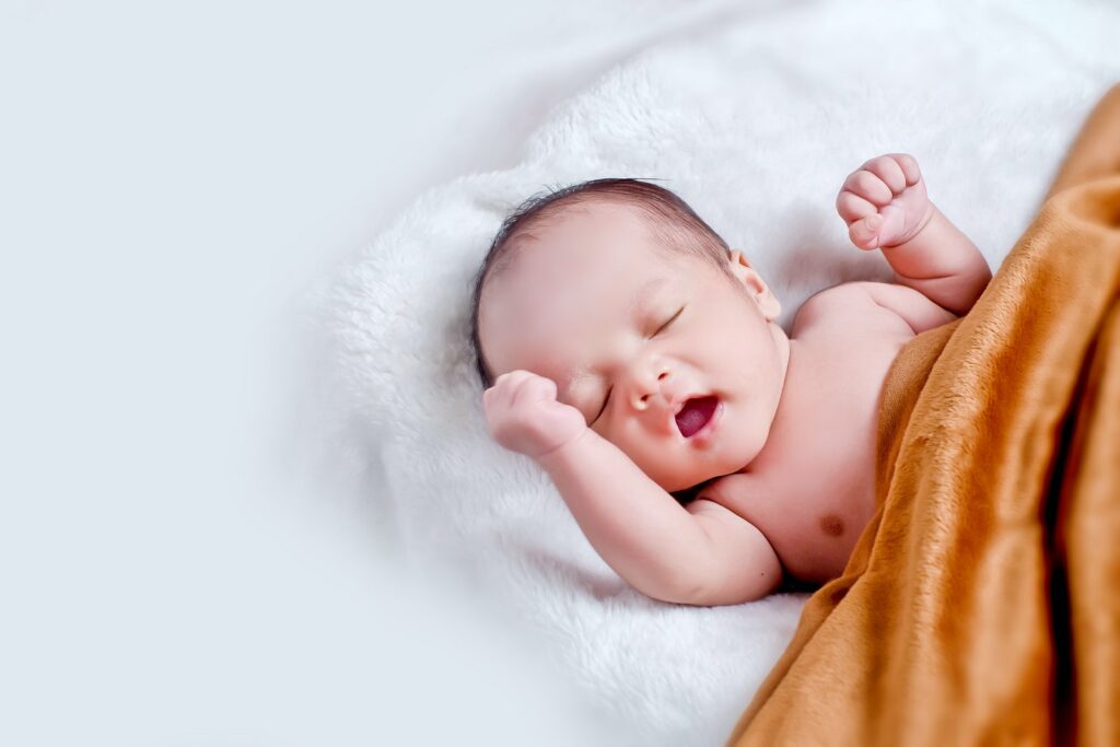 白い毛皮の上に寝そべる赤ちゃん、茶色の毛布を持つ赤ちゃん