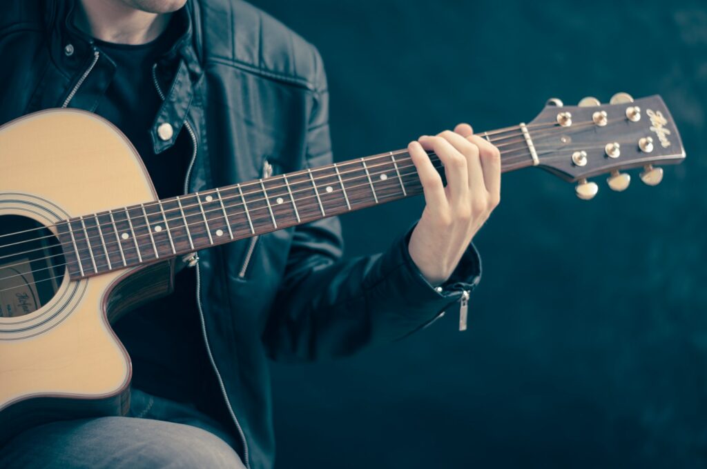 Persona con una guitarra marrón y negra en la mano