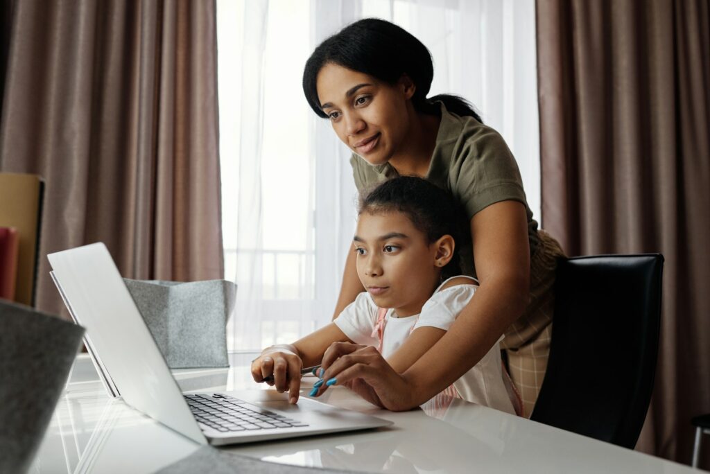 Una madre ayuda a su hija a utilizar un portátil