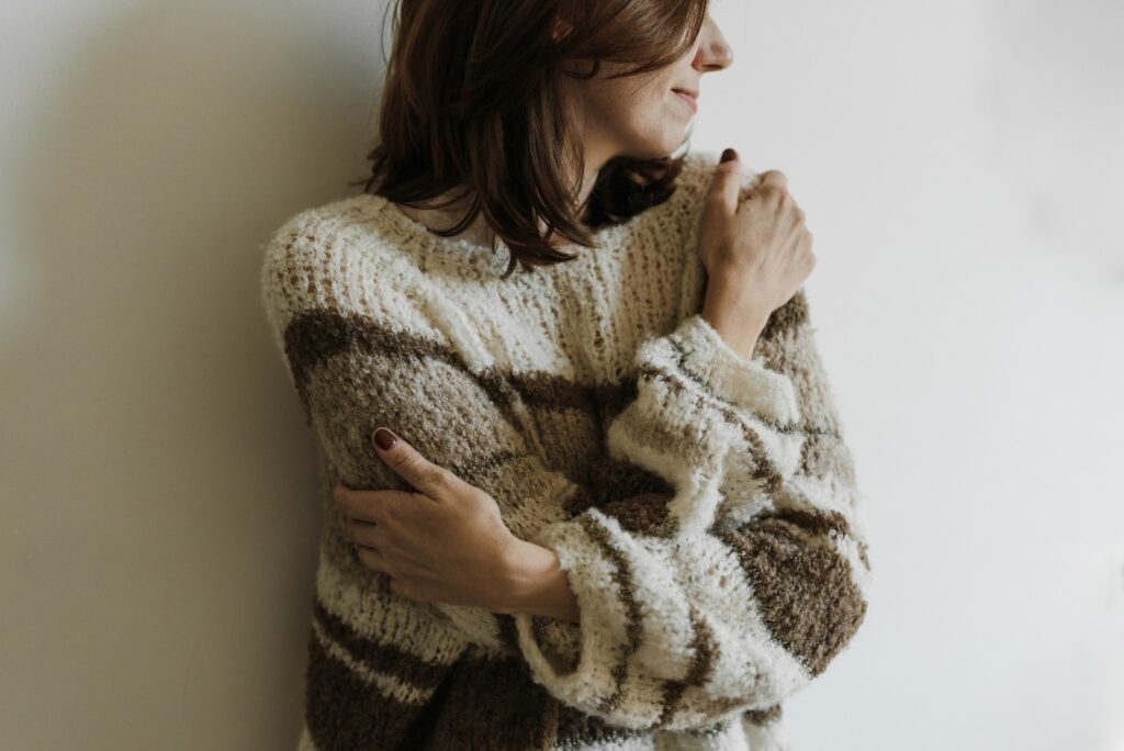 Женщина в вязаном свитере обнимает себя