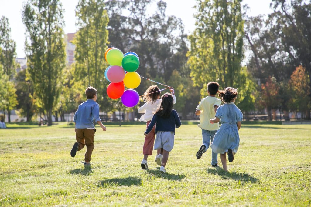 Niños jugando con globos en un campo de hierba verde