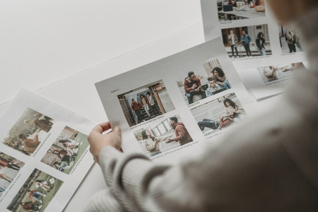 Vue de dessus d'une personne méconnaissable se préparant à créer un collage de photos d'amis multiraciaux sur des feuilles de papier.