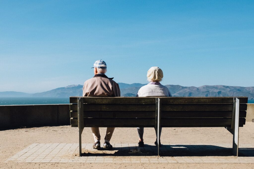 homem e mulher sentados em um banco de frente para o mar