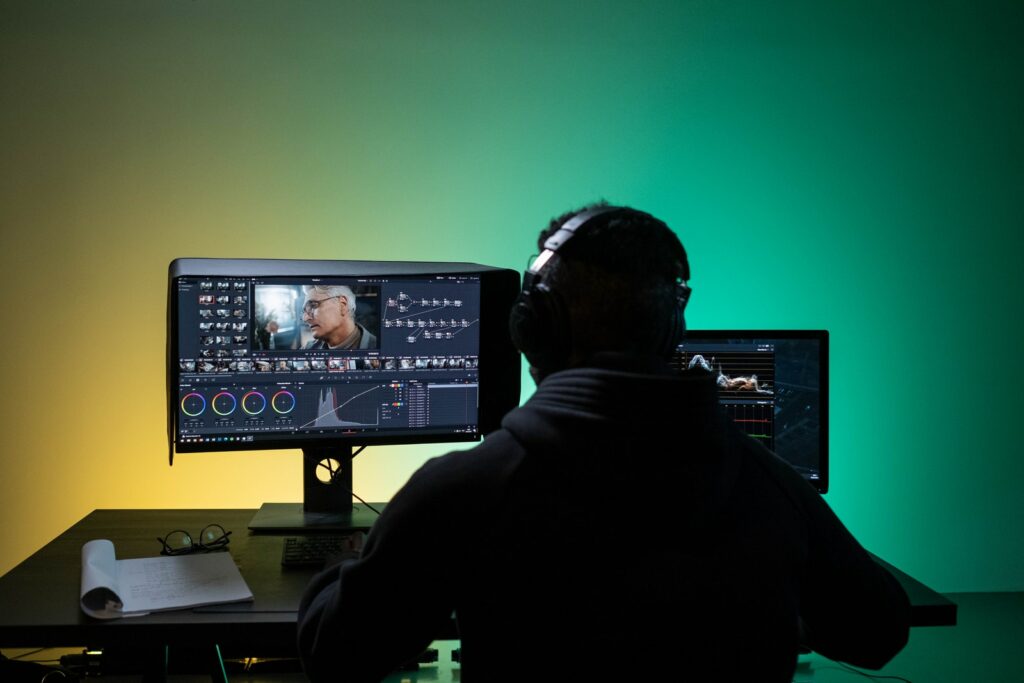 Мужчина сидит перед компьютером во время редактирования видео
