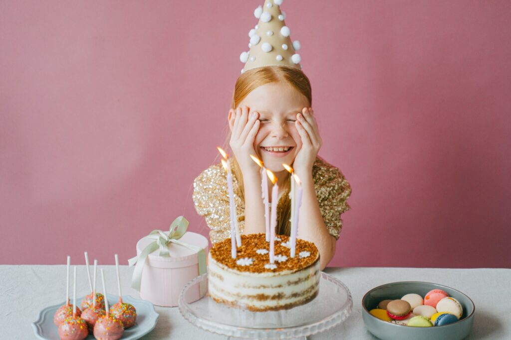 Fröhliches Mädchen im goldenen Kleid feiert ihren Geburtstag