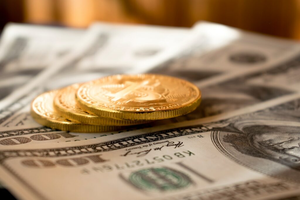 три круглые монеты золотого цвета на банкнотах номиналом 100 долларов США
