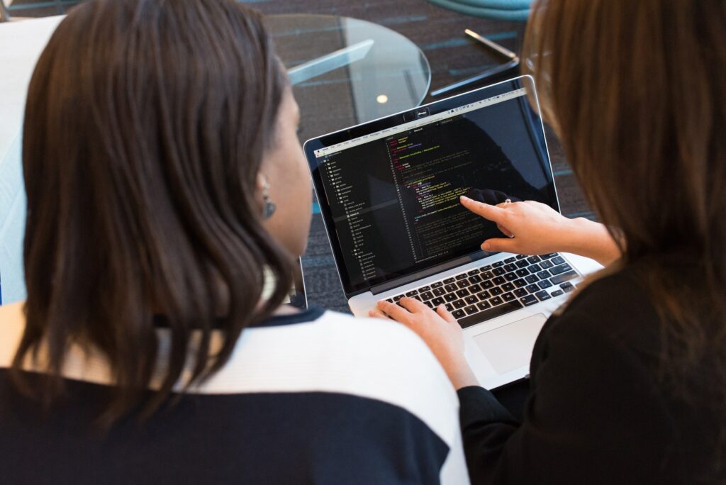 Duas Mulheres Olhando para o Código no Laptop