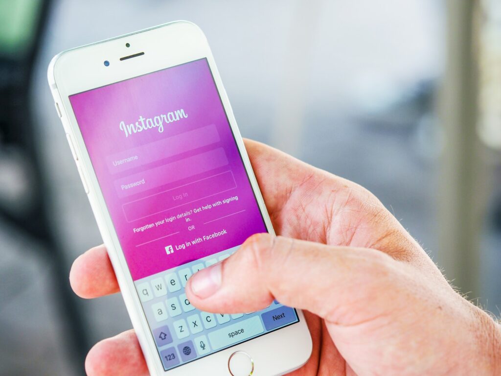 Человек держит телефон во время входа в приложение Instagram