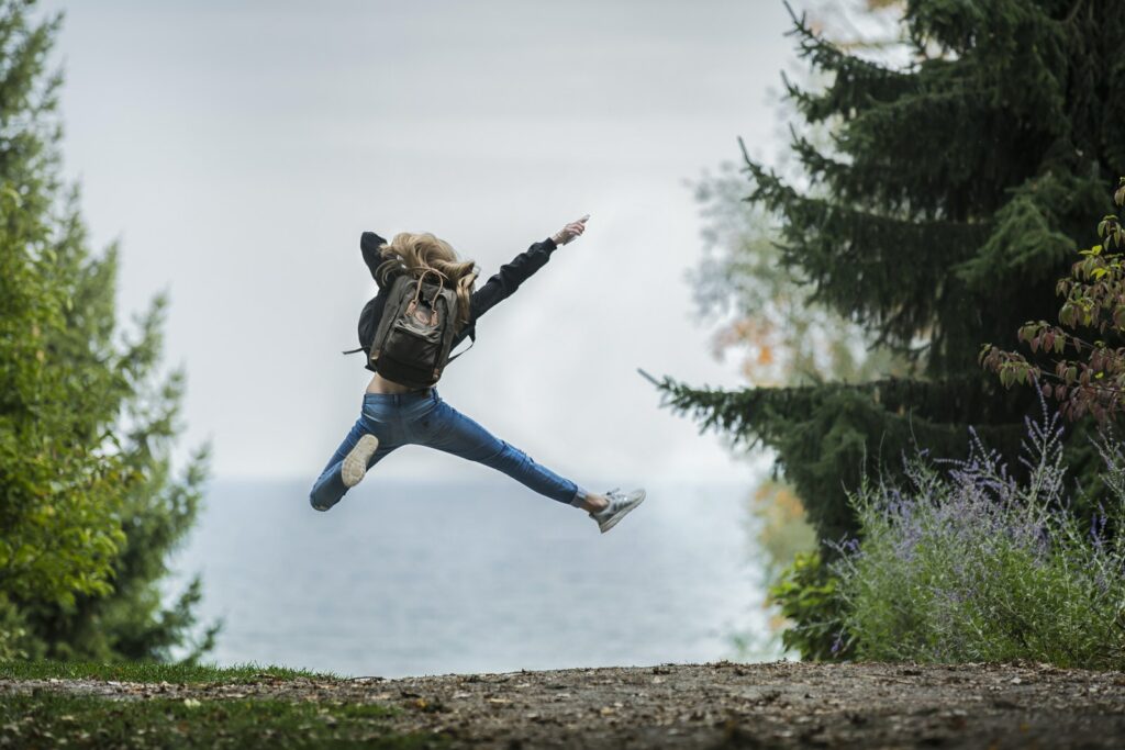 Femme sautant avec un sac à dos vert