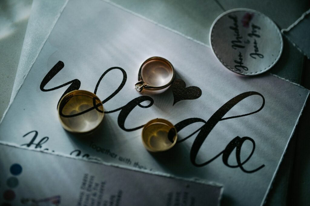 Dall'alto di costosi anelli d'oro posti su un pezzo di carta con iscrizione su un tavolo alla luce del giorno in una stanza interna