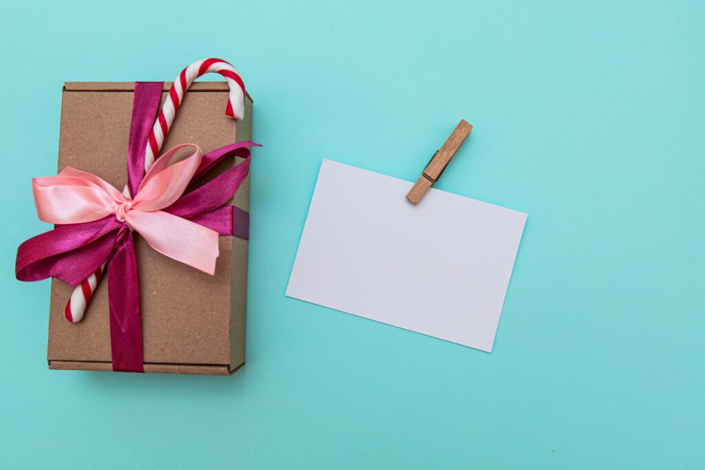 Cartolina vuota con clip disposta con scatola regalo decorata con bastoncini di zucchero