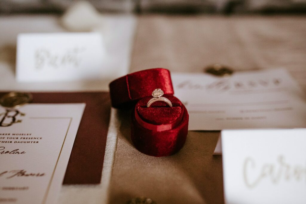 Caja roja con anillo dorado colocada sobre la mesa con tarjetas de invitación