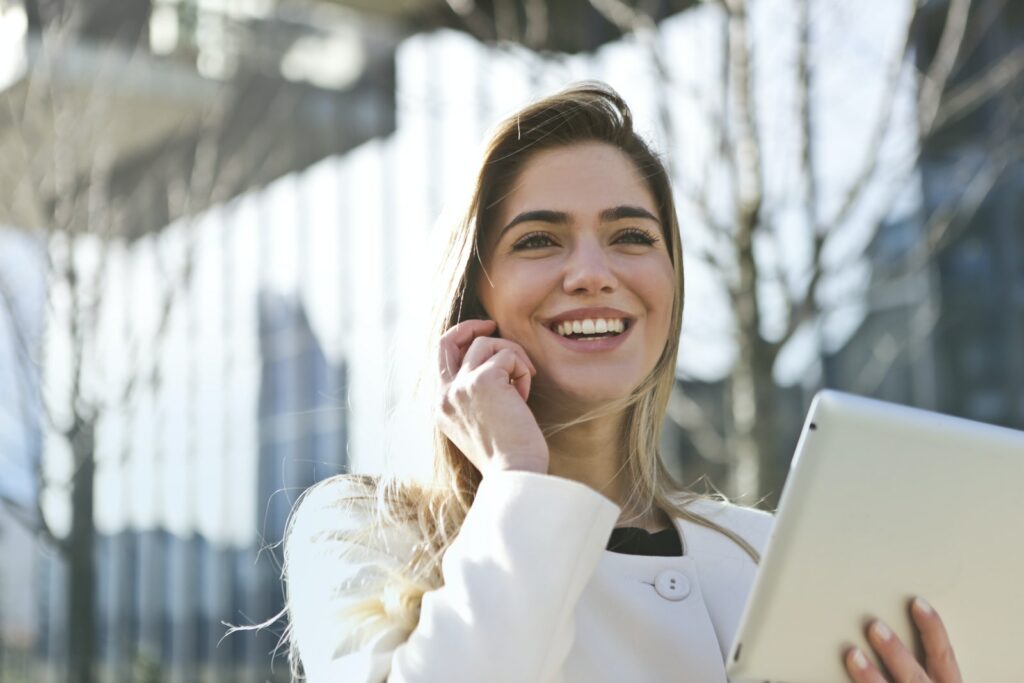 Donna con blazer bianco che tiene in mano un computer tablet