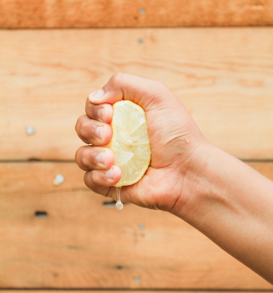 Foto de fechamento de uma pessoa espremendo um limão suculento