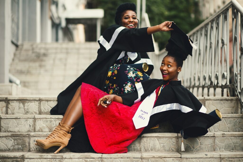 Photographie en contre-plongée de deux femmes en robe académique sur une volée d'escaliers