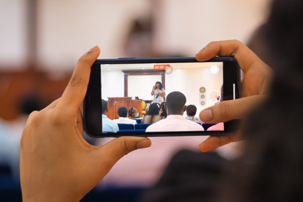 Person, die ein silbernes Iphone 6 hält und ein Foto von Menschen auf einer Bank macht