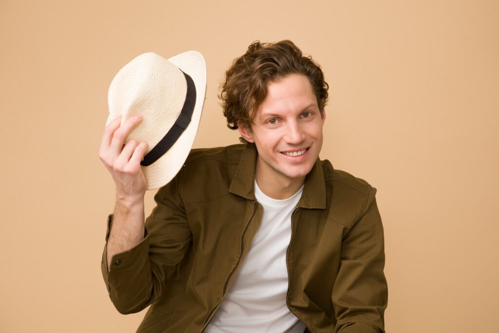 Hombre con camisa de vestir marrón sosteniendo sombrero de fieltro blanco