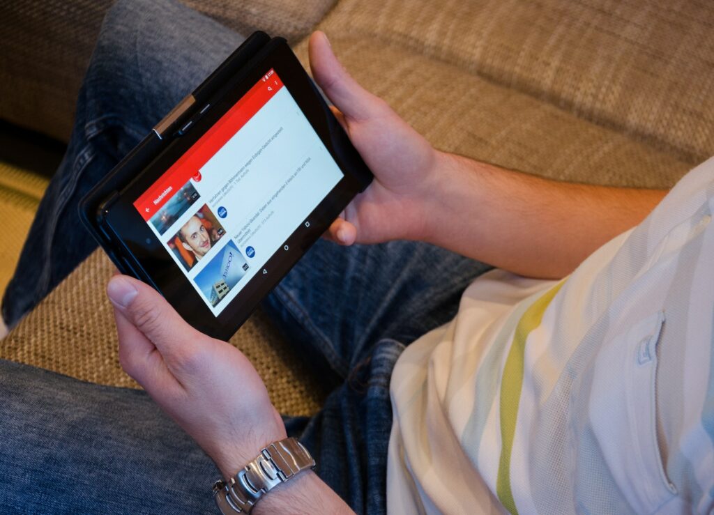 Persona che tiene in mano un computer tablet e mostra dei video