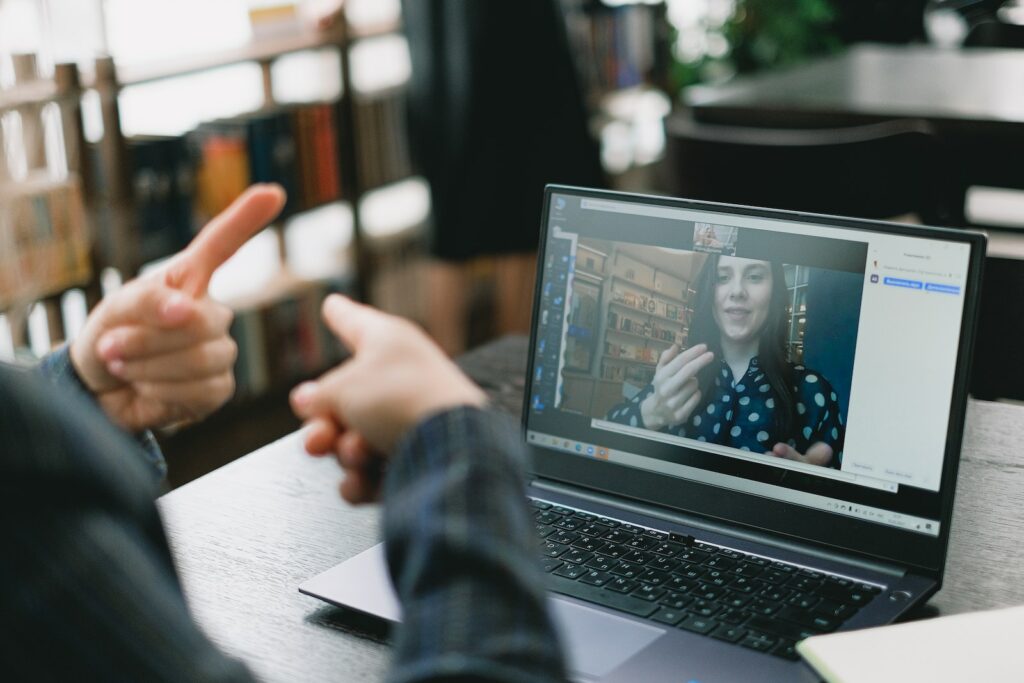 Jovem aprendendo linguagem de sinais durante aula on-line com tutor feminino